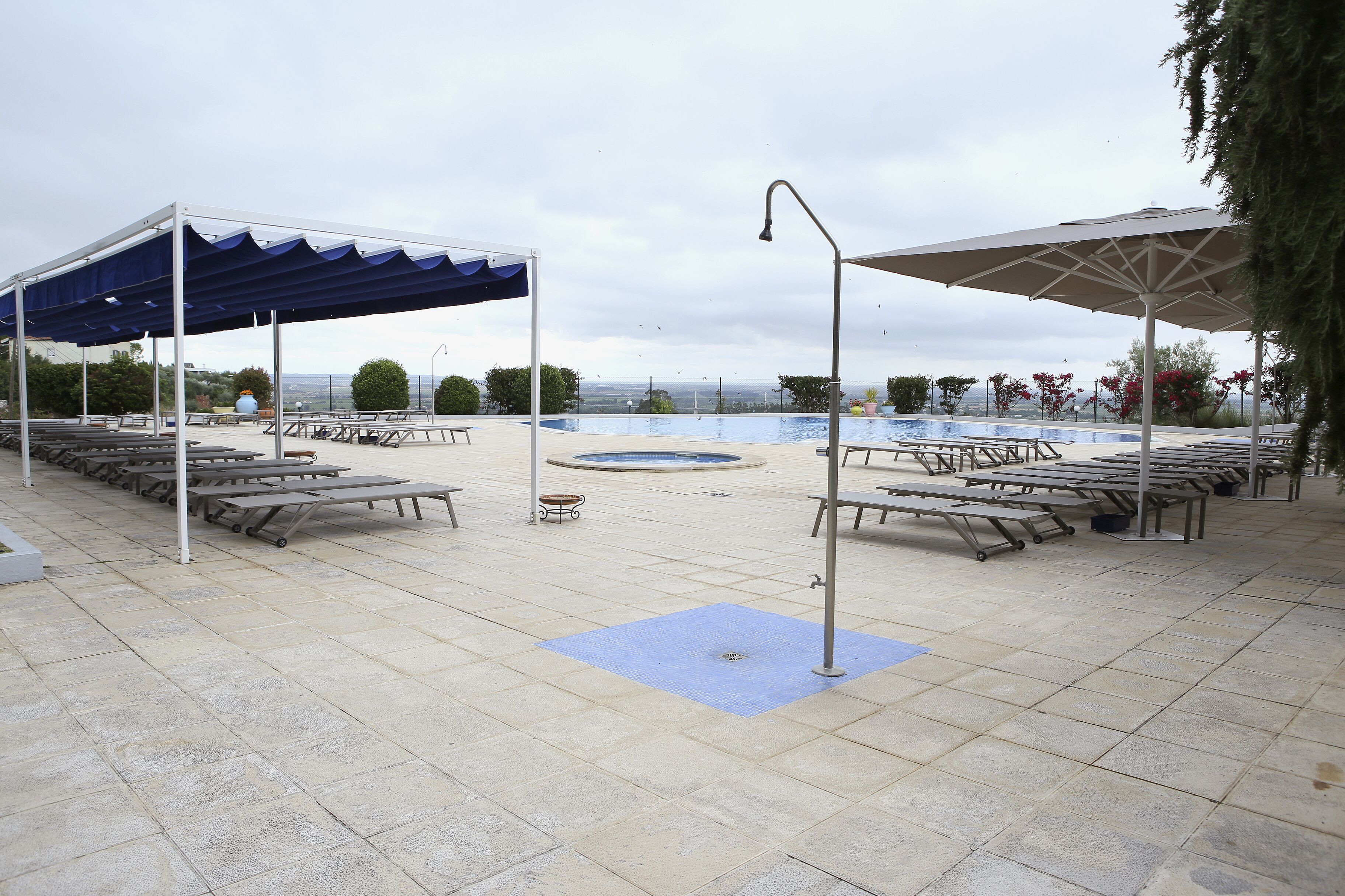 Area piscina con posti a sedere coperti e vista sull'acqua.