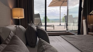 Habitación de hotel con cama, almohadas, lámpara, ventana con vistas al exterior y una silla.