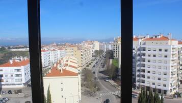 A cityscape with multiple buildings, a clear sky, and a view of the sea in the distance.