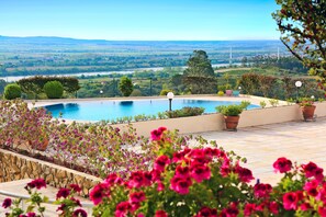 A pool with a view of a river and distant landscape, surrounded by potted plants and flowers. - Verdi Santarem (Santarém)
