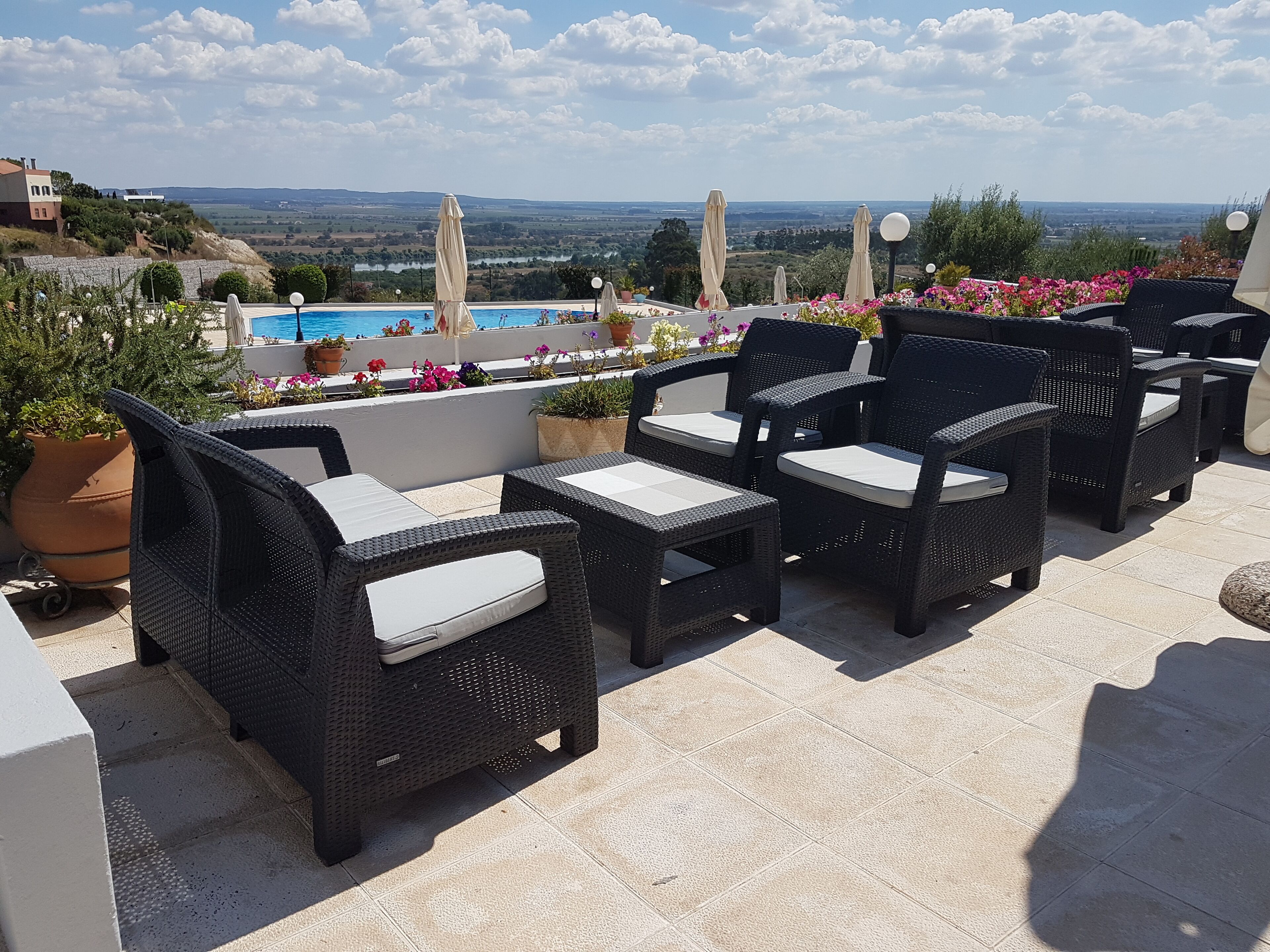 Outdoor wicker furniture with cushions, a pool, and a view of the countryside.