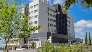 Un hotel moderno con un llamativo letrero que dice 'HOTEL', varios pisos y un estacionamiento visible al fondo.
