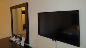 Une pièce dotée d’un grand miroir et d’un téléviseur à écran plat fixé au mur.