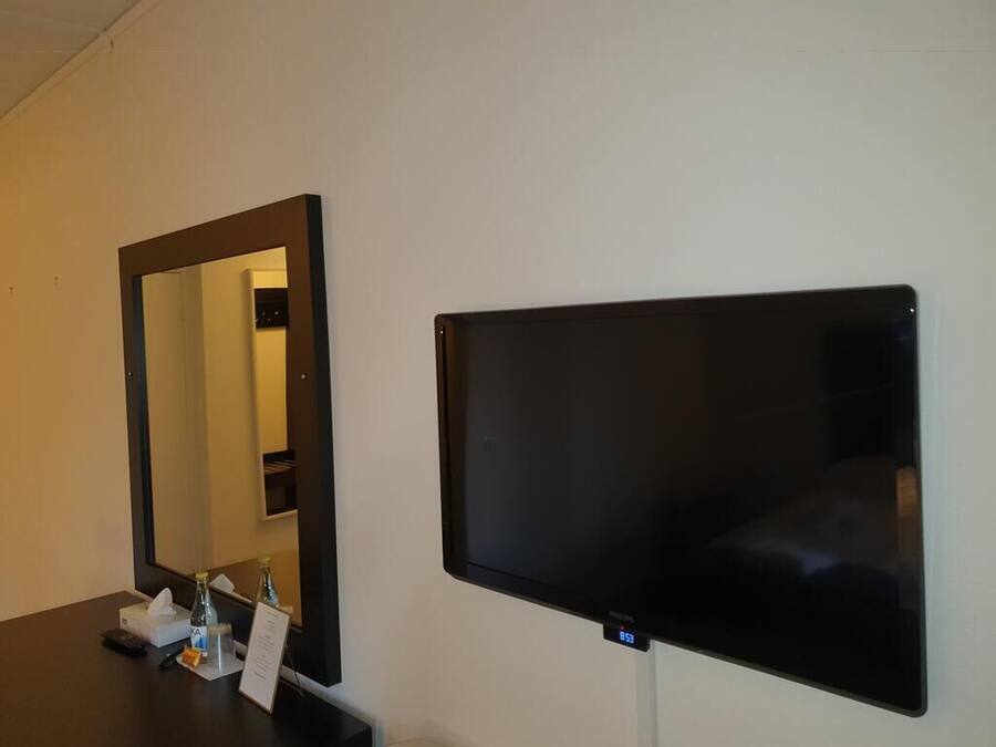 Una stanza con un grande specchio e una TV a schermo piatto fissata al muro.