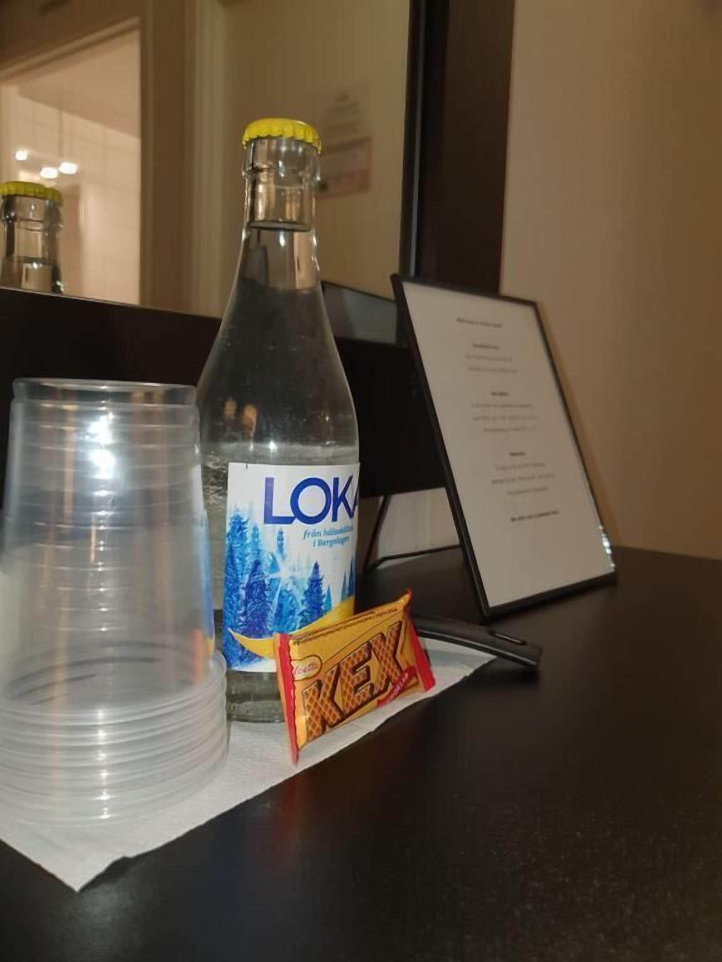 Una botella de agua LOK, un vaso y una tableta de helado Rex sobre una mesa.