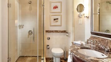Ein modernes Badezimmer mit einer gläsernen Duschkabine, einem мраморнем Waschbecken und einer Toilette.