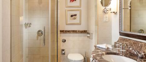 A modern bathroom with a glass-enclosed shower, a marble sink, and a toilet.