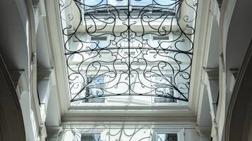 A high-ceilinged atrium with ornate ironwork and multiple windows.
