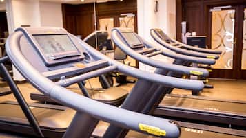 A row of treadmills in a gym with a mirrored wall and wooden paneling.