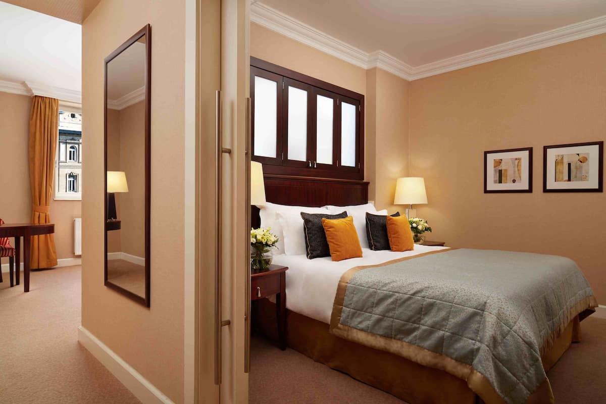 Een hotelkamer met een bed, bedlampen, een spiegel en twee ingelijste foto’s aan de muur.