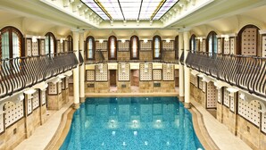 Una amplia piscina interior con una isla central, rodeada por una zona de estar con barandilla.