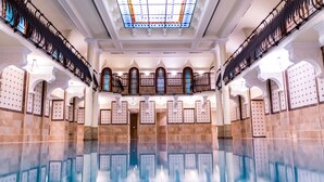 Una piscina amplia en el interior, con techo alto y barandillas decorativas.