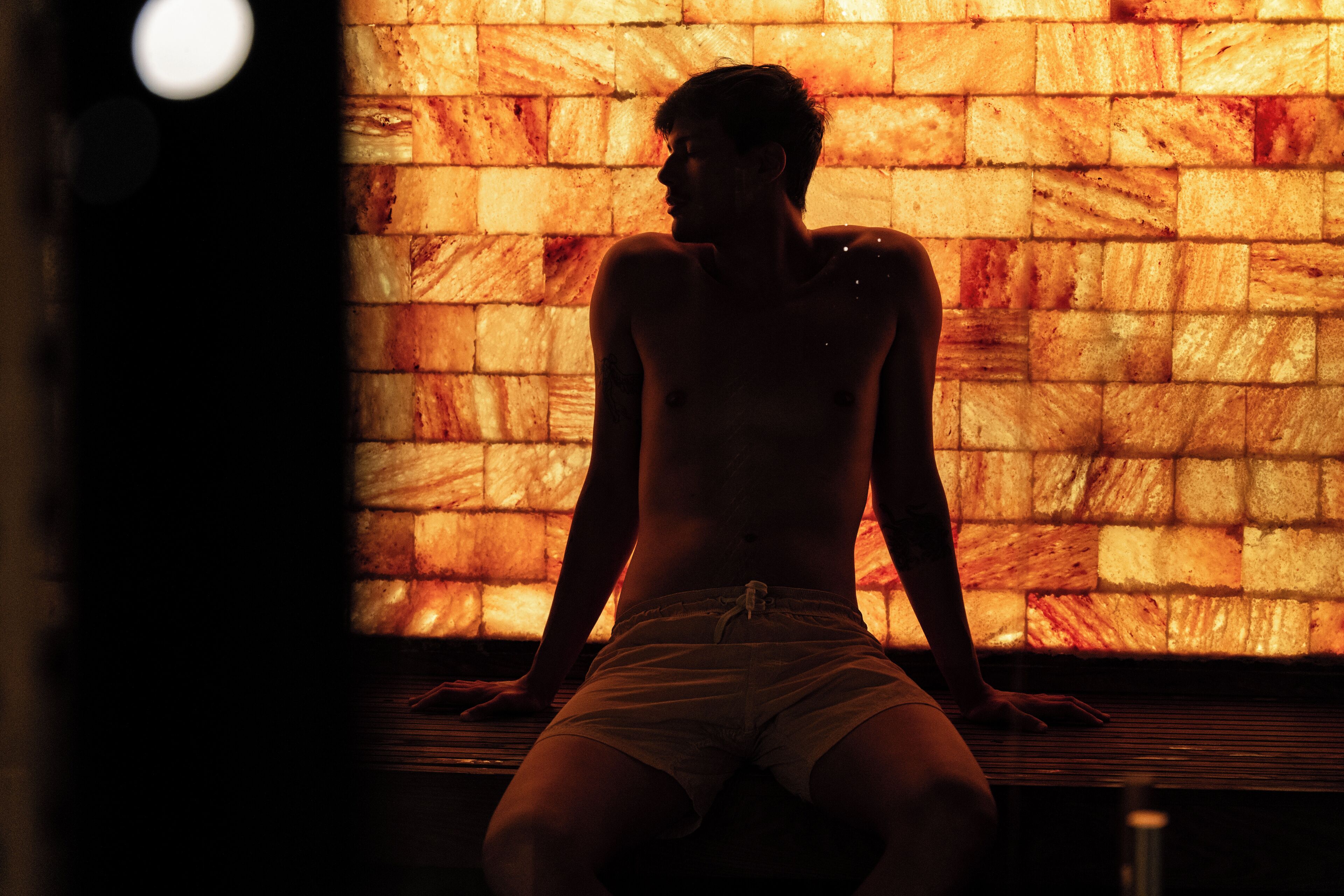 A person sitting in a sauna with a brick wall in the background.