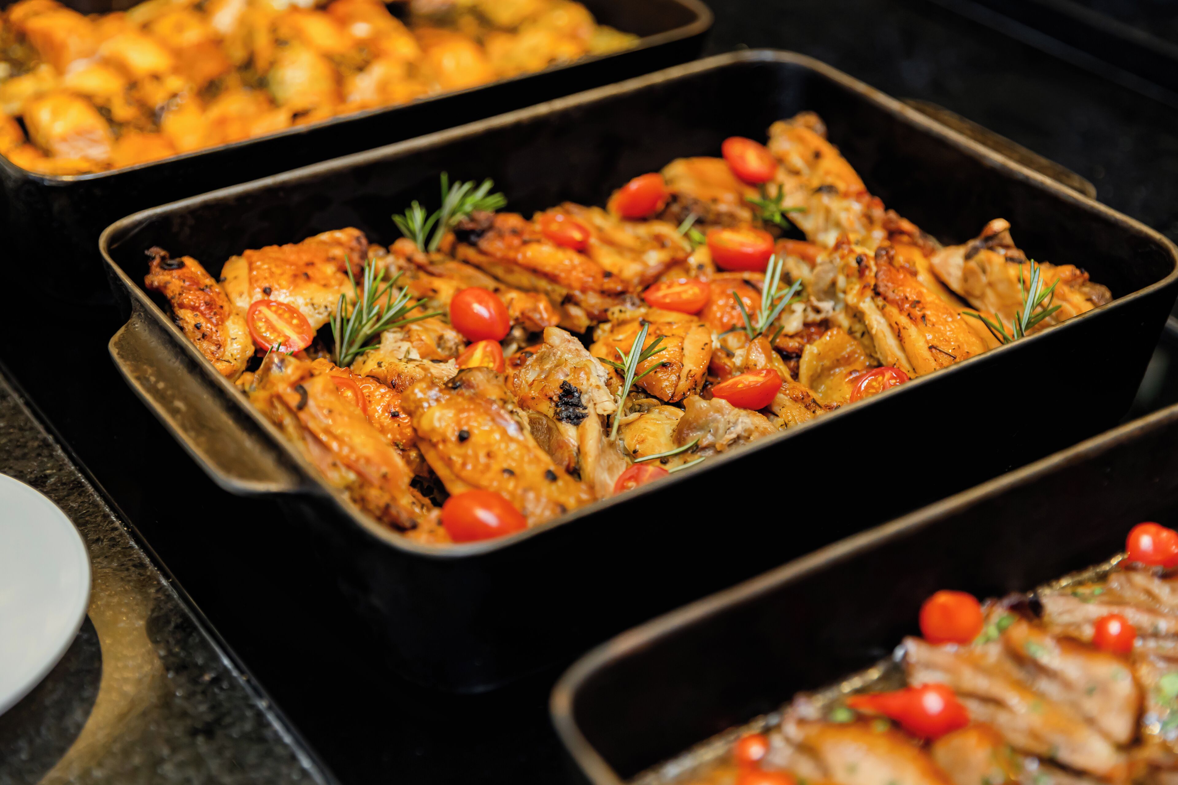 A buffet with roasted chicken and vegetables.