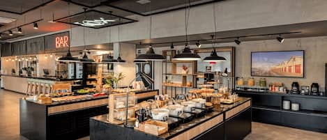 A modern bar area with a neon sign, pendant lighting, and a variety of food and drink options.