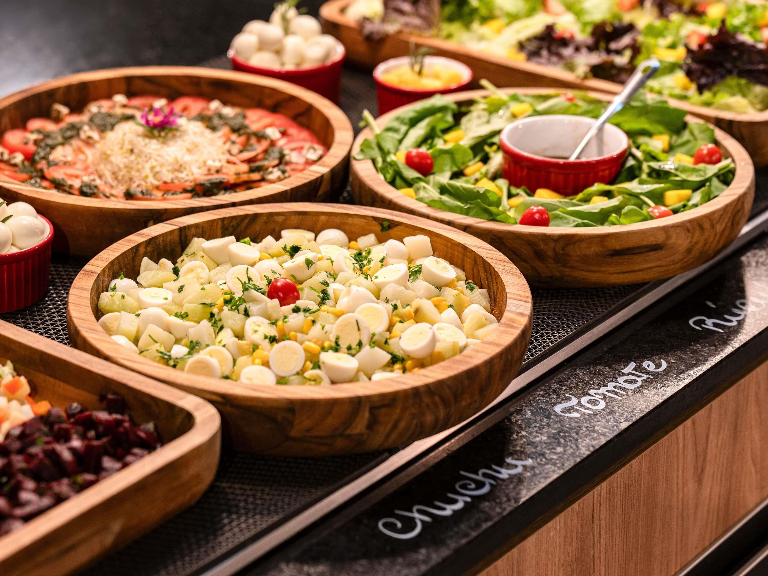 A buffet table with various food options in wooden bowls.