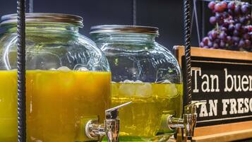 Un dispensador de bebidas con tres frascos de vidrio que contienen líquidos, un grifo metálico y un cartel con texto.