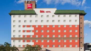 Experience the contemporary design of ibis HOTEL, featuring a symmetrical facade with multiple windows.