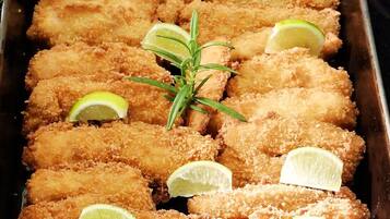 A tray of breaded and fried food items garnished with lime slices and a sprig of rosemary.