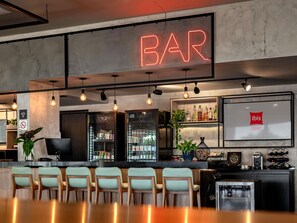 A bar area with a neon sign, seating, and a display of beverages. - ibis Porto Alegre Aeroporto (Porto Alegre)