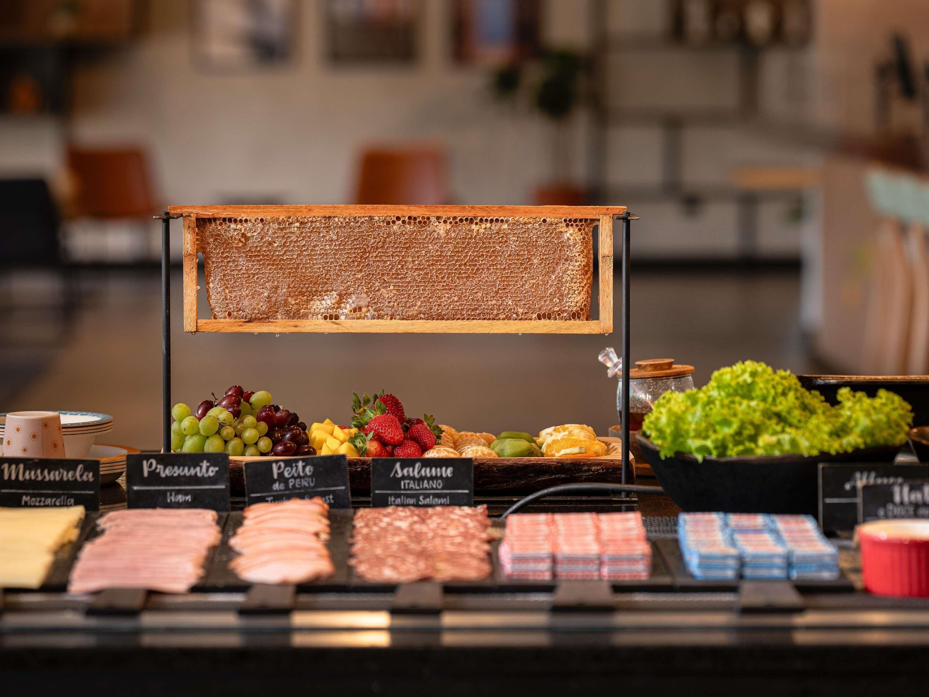 A food display with various cheeses, meats, and fruits.