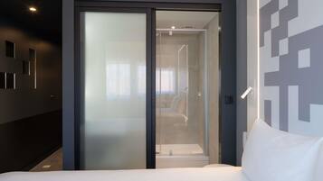 Una habitación de hotel con una cama, una puerta corredera que da a un baño y una pared con diseños geométricos.