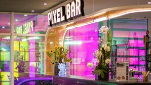 A Pixel Bar with a neon sign, a bar counter, and a display of flowers. - ibis Styles Béziers Centre (Béziers)