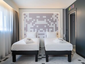 A hotel room with two beds, a pixelated wall art, a phone, and a door with a sign.
