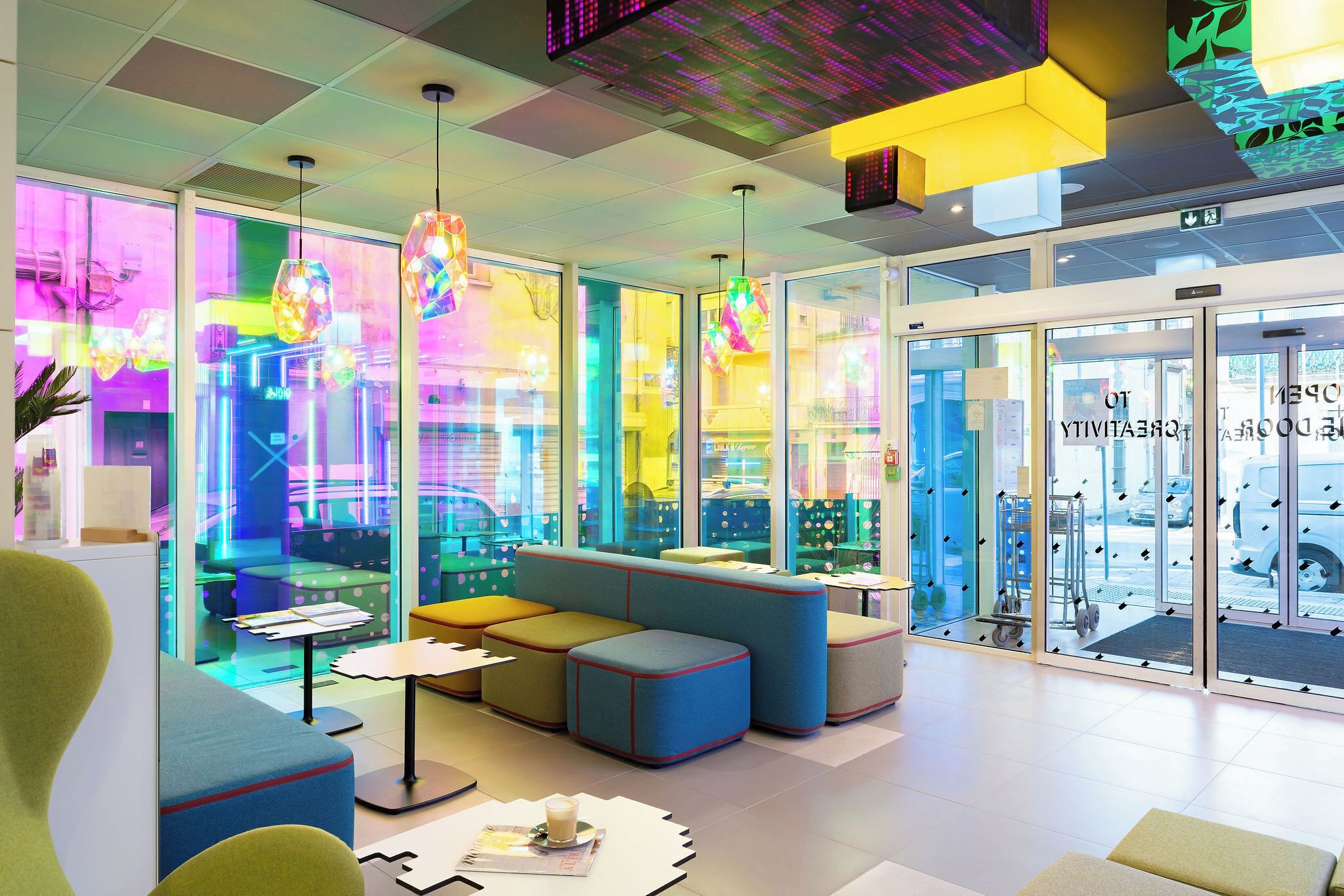 A modern interior with seating areas, glass walls, and colorful lighting.