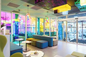 Un intérieur moderne avec des espaces de détente, des murs en verre et un éclairage aux couleurs vives.