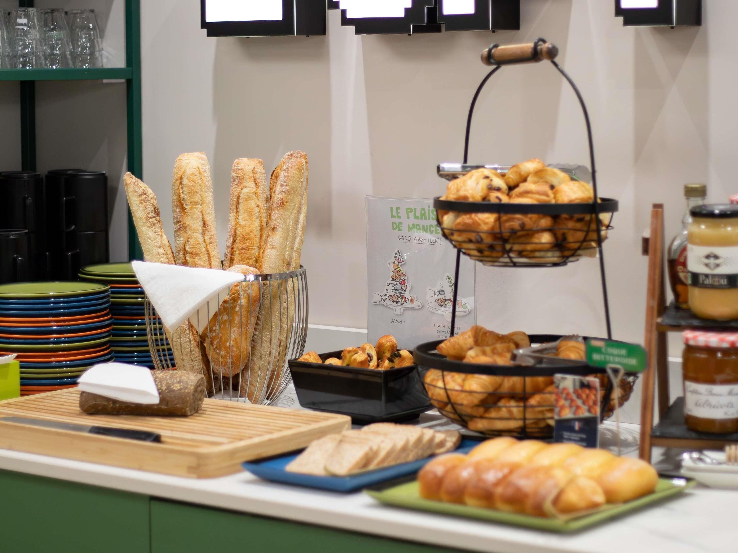 A buffet setup with bread, pastries, and condiments.