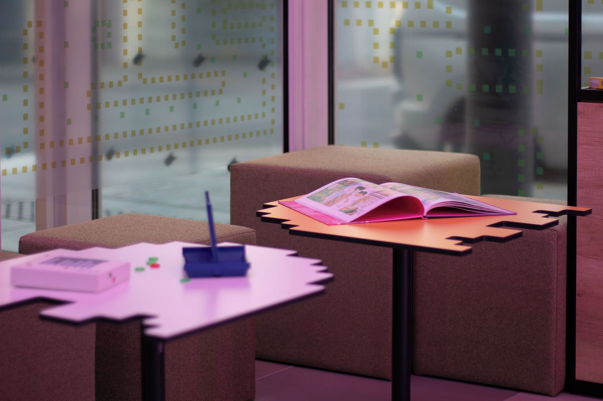 Habitación moderna y minimalista con un sofá, una mesita con un libro, y una pared con diseño geométrico.