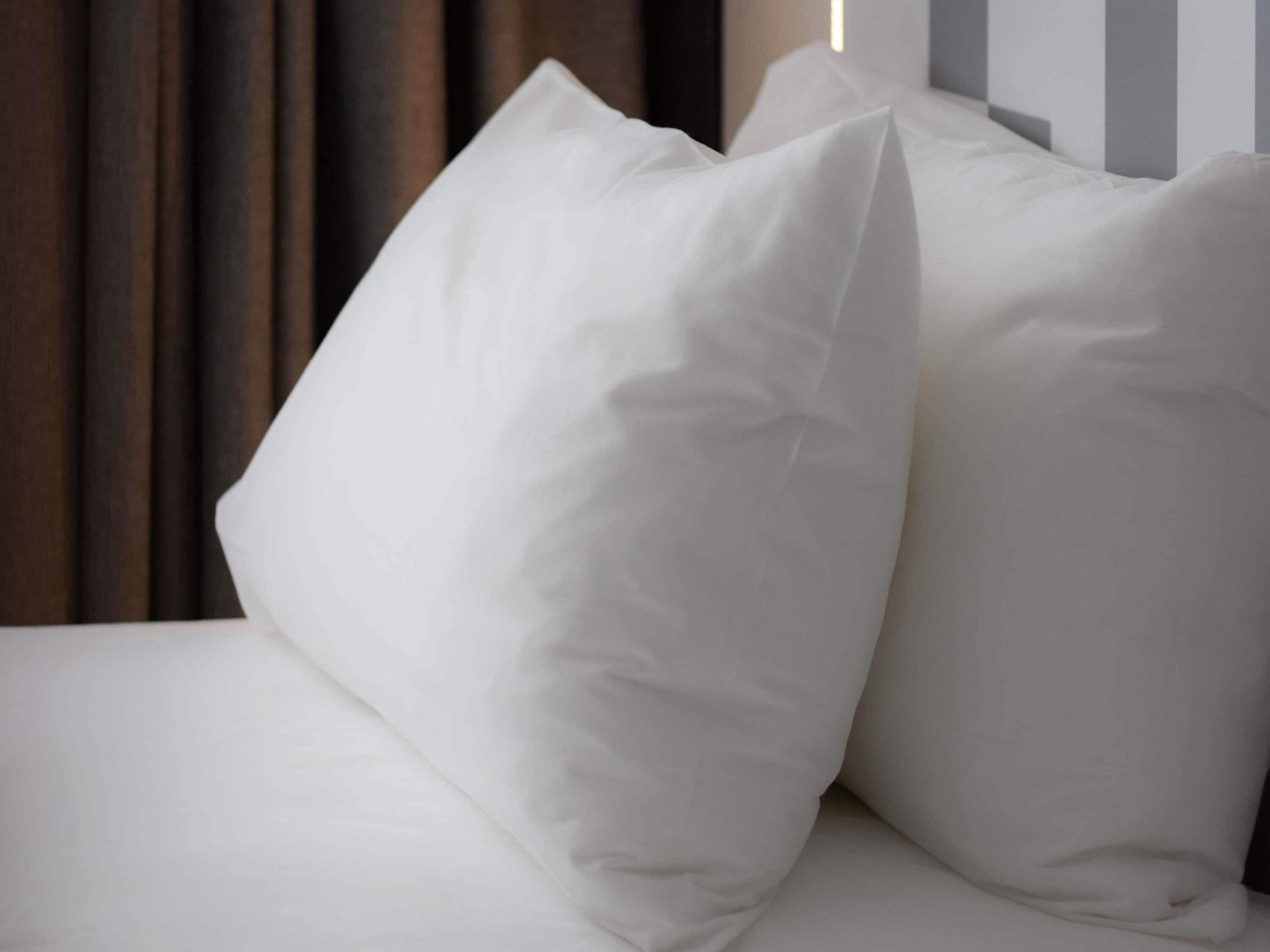 A bed with white bedding and two pillows.