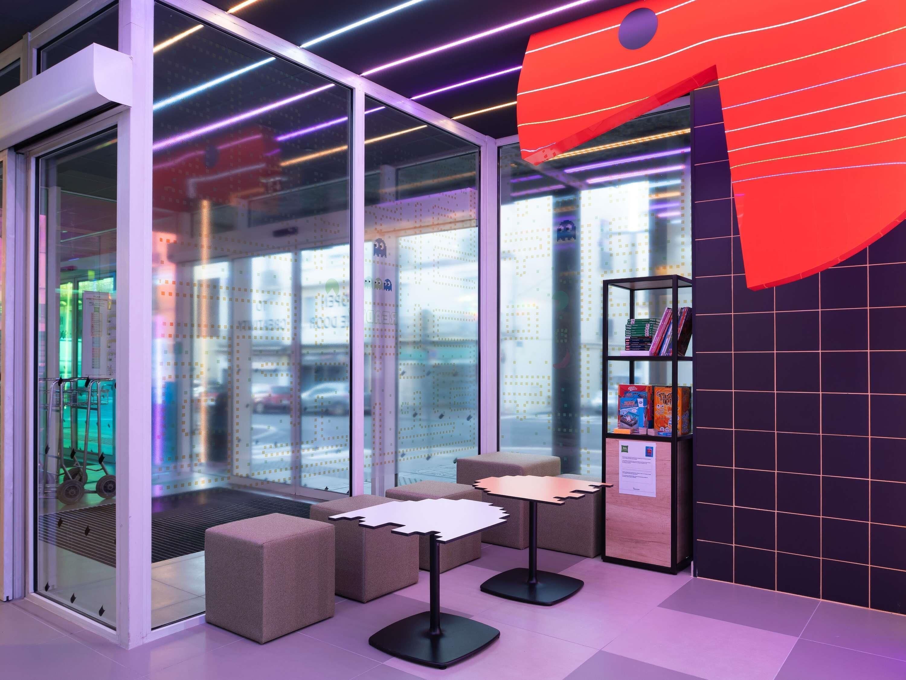 Un interno moderno con pareti divisorie in vetro, un'opera d'arte astratta rossa e una libreria piena di libri.