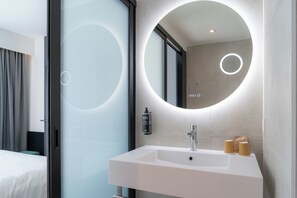 Un baño moderno con un espejo grande, un lavamanos blanco y una botella de jabón de manos.