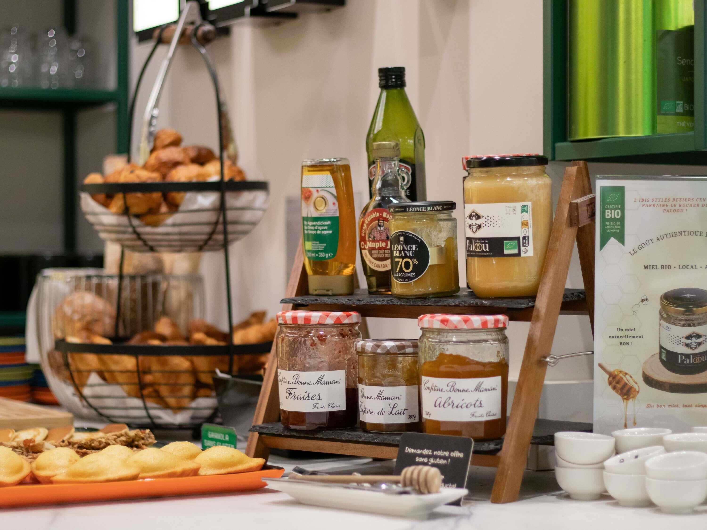 Un buffet proposant une variété de plats, notamment des pâtisseries, des confitures et du miel.
