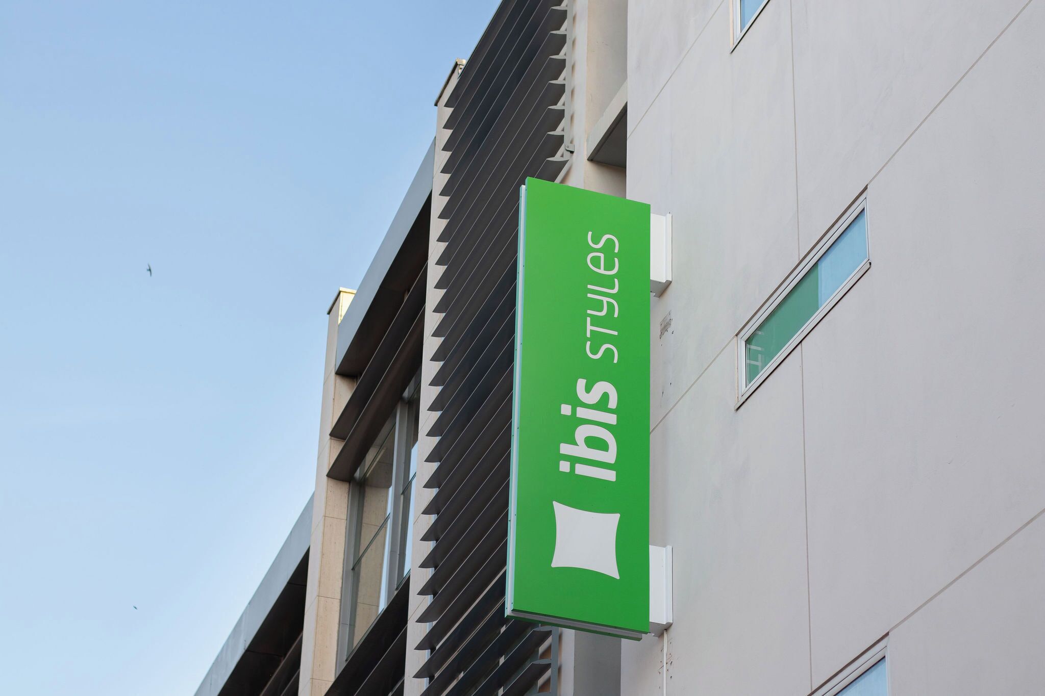 A building with a sign that reads 'ibis styles' on a green background.