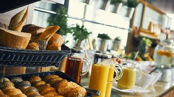 Un bufé de desayuno con panes y zumos variados.