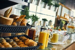 A breakfast buffet with various breads and juices.