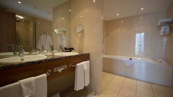 A modern bathroom with two sinks, a large mirror, a bathtub, and a shower.