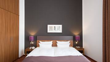 A hotel room with a large bed, two bedside tables, a wardrobe, and a framed picture on the wall.