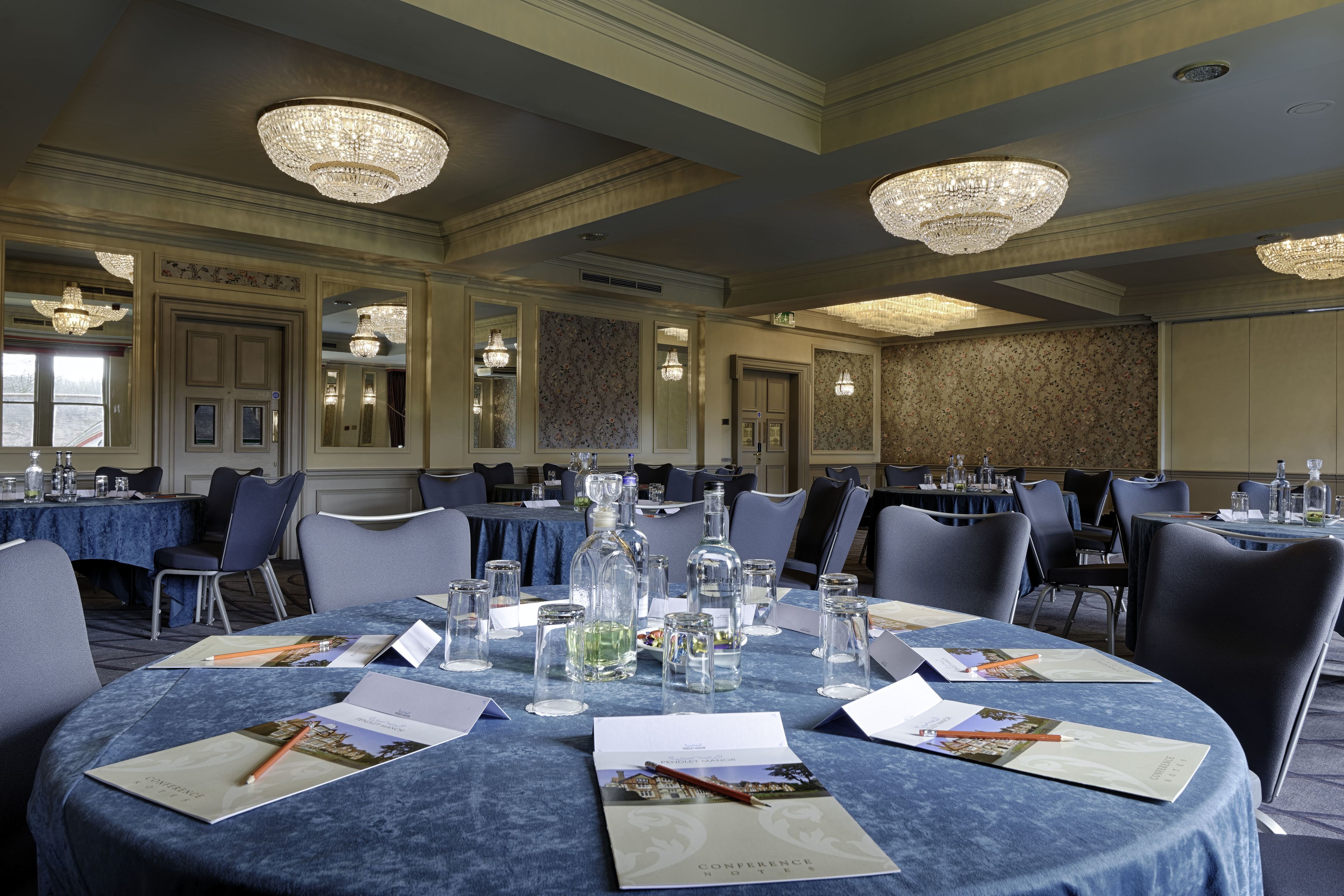 Une salle de conférence équipée de tables rondes, de chaises et de lustres.