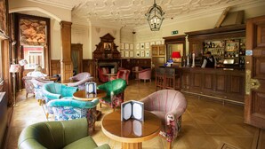 A hotel lobby with ornate ceiling, multiple seating areas, a bar, and a fireplace. - Pendley Manor (Tring)