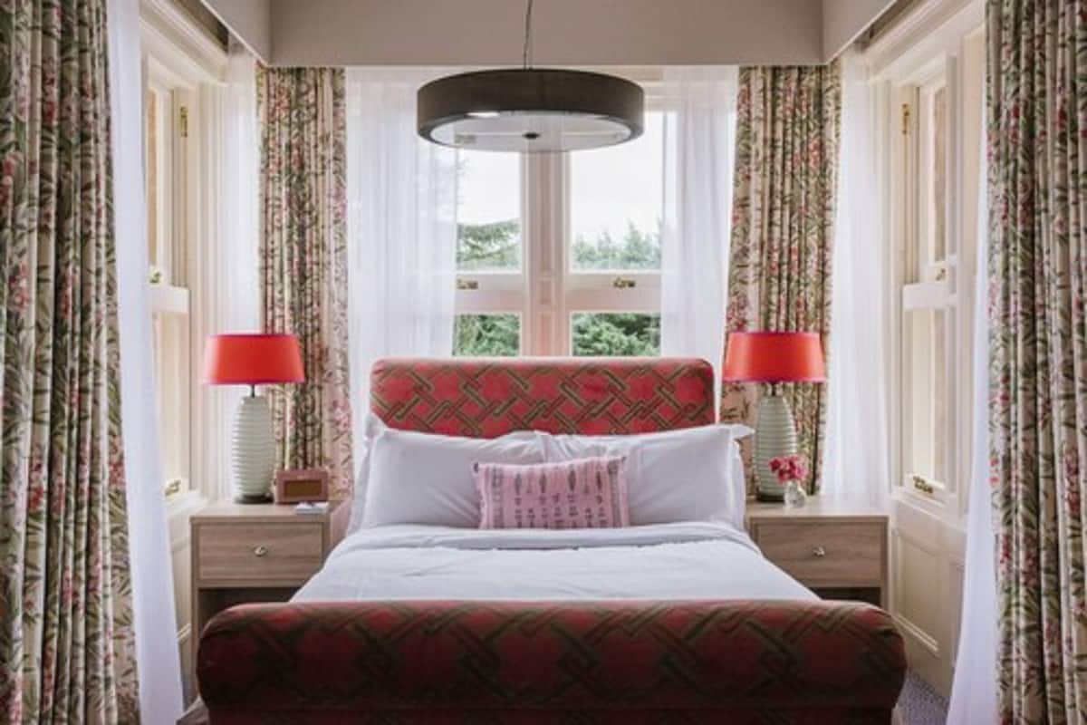 Ein ordentlich eingerichtetes Schlafzimmer mit einem Bett, zwei Nachttischen und einem Fenster mit Vorhängen.