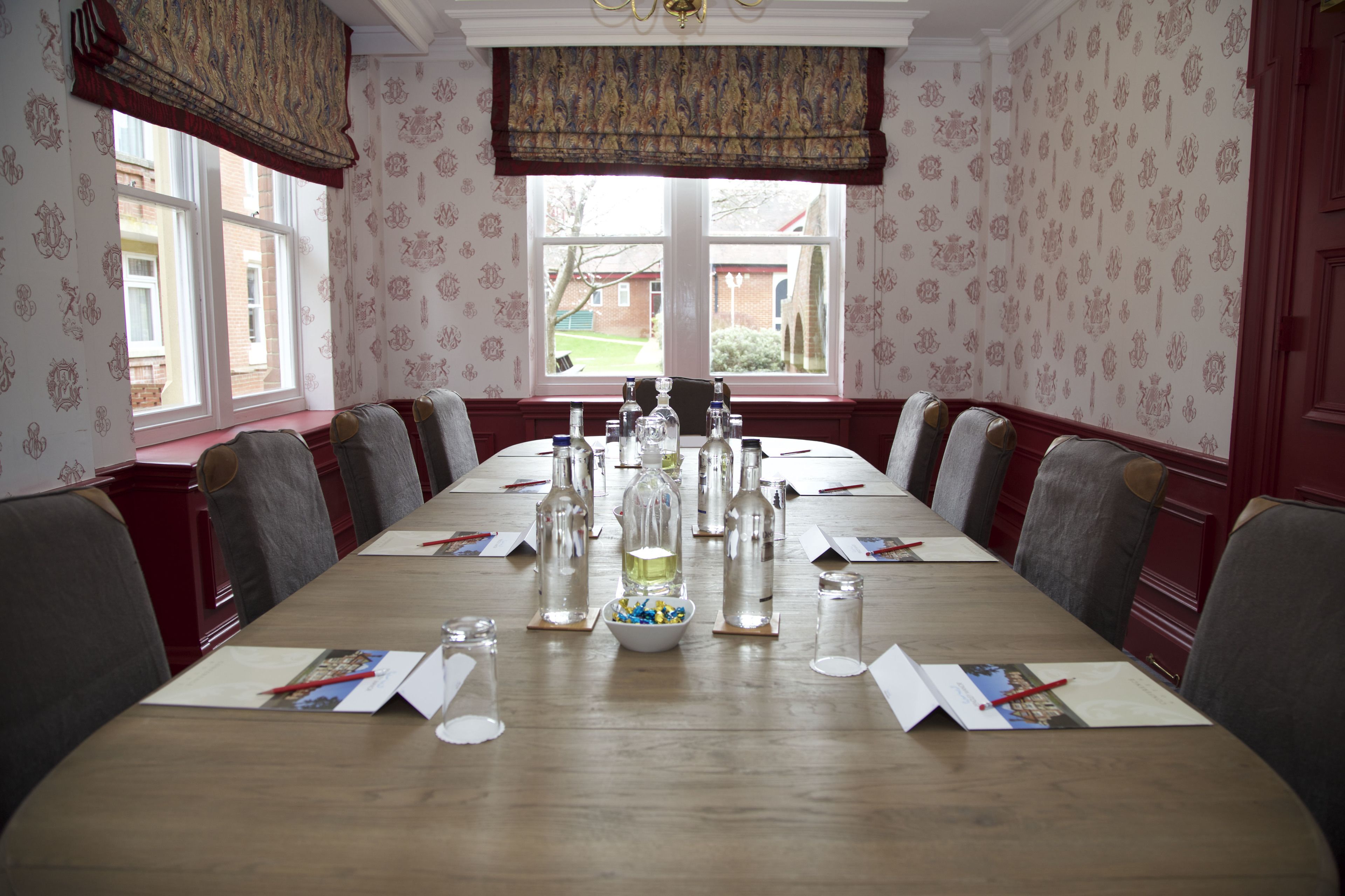 A conference room with a long table, chairs, and various items like bottles and papers.