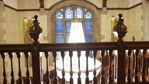 A grand staircase with a chandelier, ornate balustrades, and stained glass windows. - Pendley Manor (Tring)