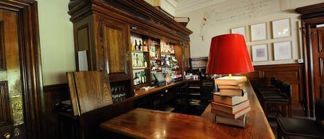A bar area with wooden furniture, a red lamp, and a bar counter with a cash register.