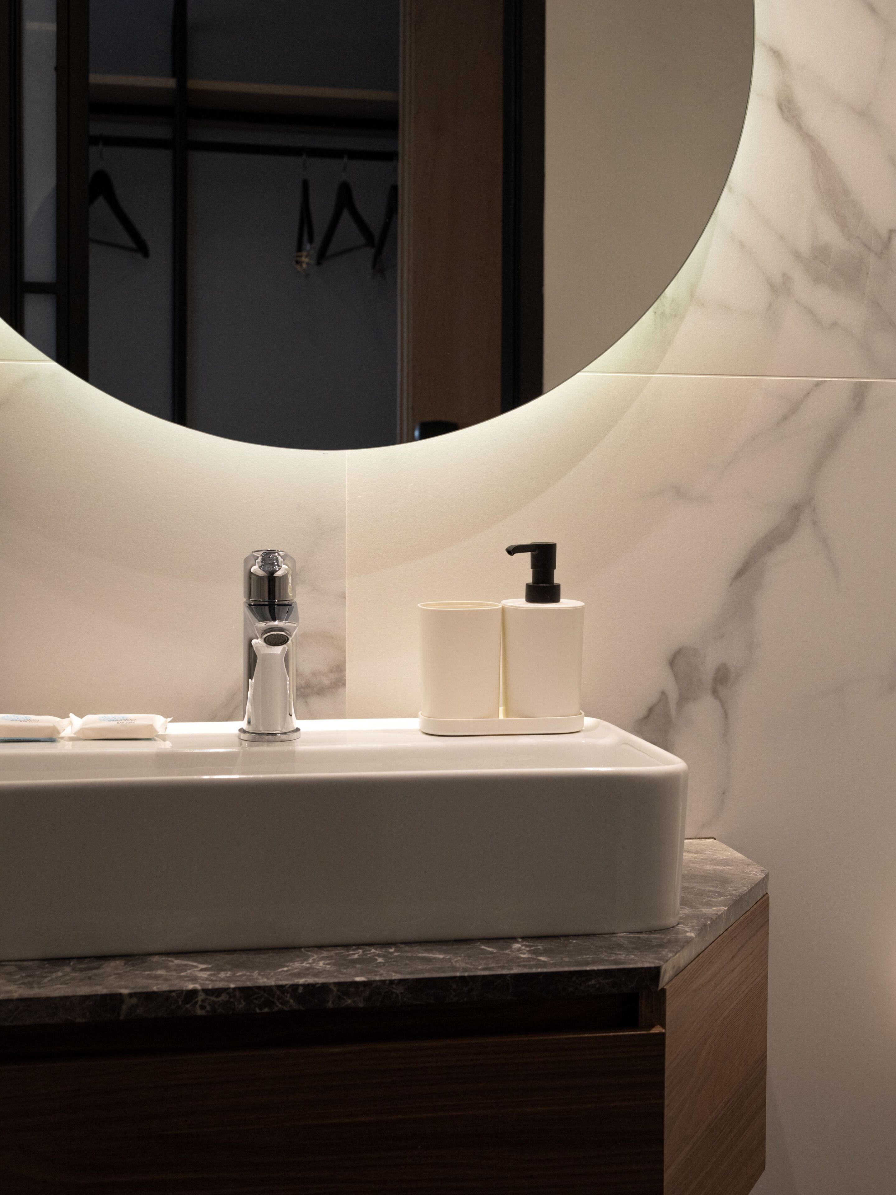 A bathroom with a white sink, a modern faucet, and a soap dispenser.