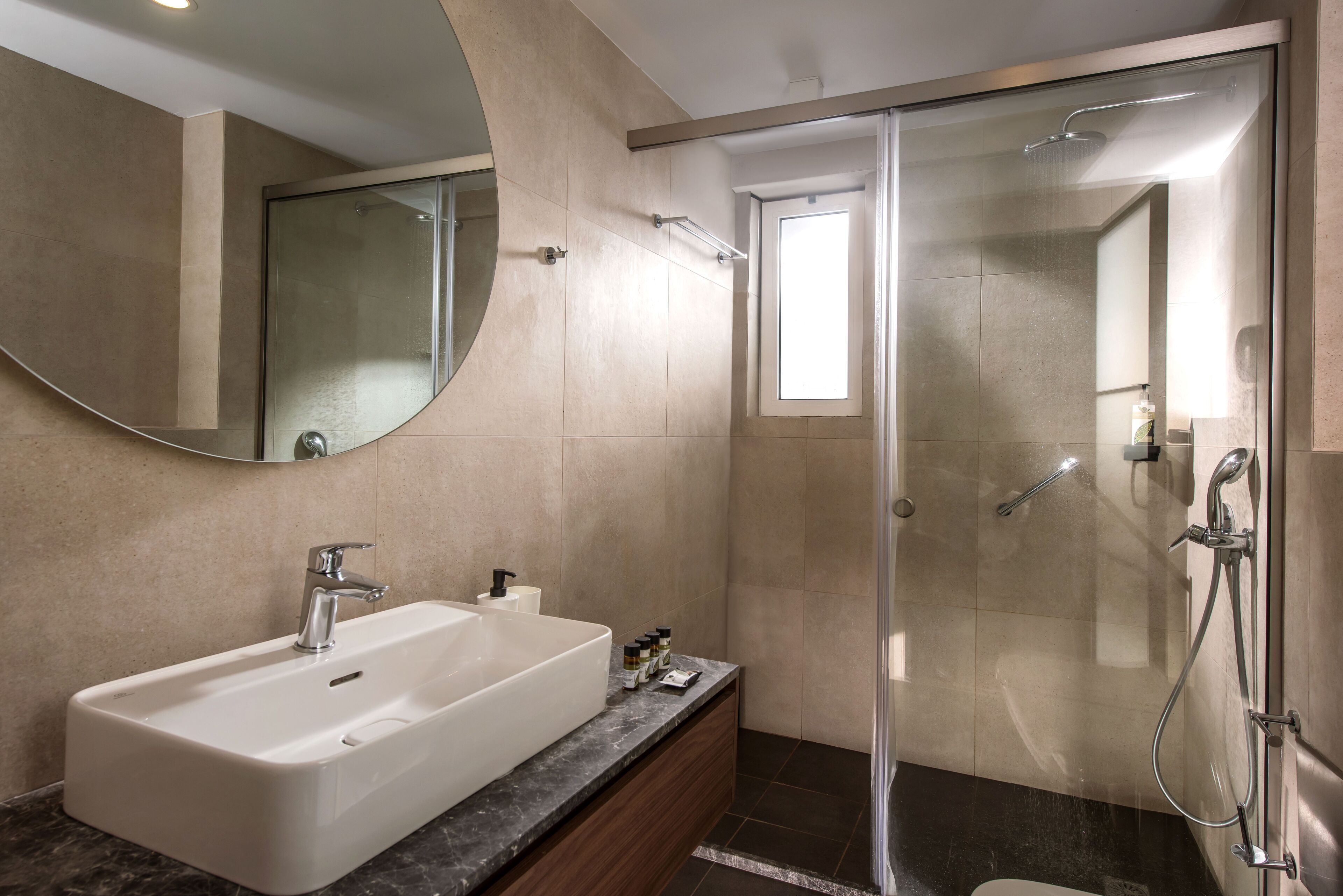 A modern bathroom with a large sink, a glass shower enclosure, and a mirror.