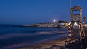 Une plage avec une tour de surveillance en bois et une mer calme au crépuscule.